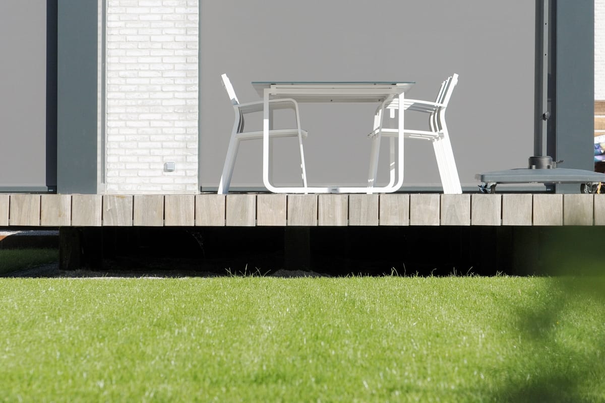 Zwevend houten terras in padoek boven een strak gemaaid gazon